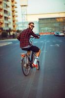 hombre en Gafas de sol montando un bicicleta en ciudad calle foto