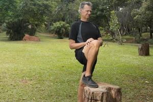 Mature Man outside at a local park doing Stretching his leg before working out photo