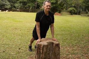 maduro hombre fuera de a un local parque haciendo estiramientos antes de trabajando fuera foto