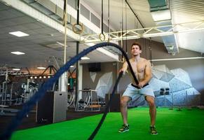 hombre con batalla cuerda en funcional formación aptitud gimnasio foto