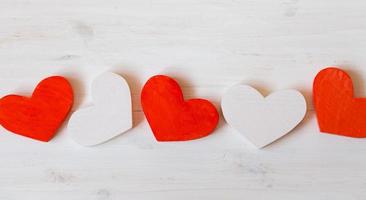 Red and white hearts on white wooden background photo