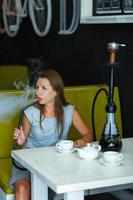 Beautiful woman smoking a hookah and drinking tea in a cafe photo