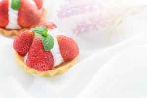 Strawberry Tart with mint leaf on cream cheese on white cloth background, photo