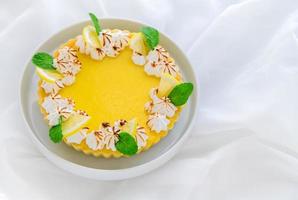 Lemon Tart citrus cake in white dish and white cloth background, photo