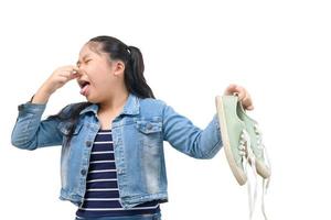 joven asiático niña sensación infeliz con malo oler zapatilla de deporte Zapatos aislado foto