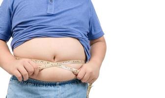 Obese boy measures his fat belly with a measuring tape isolated on white photo