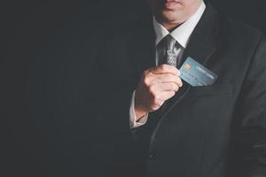 Businessmen take out the credit card from the suit pocket on black background, photo