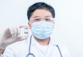 doctor or scientist in gown shirt holding COVID-19 vaccines. medical and science concept photo