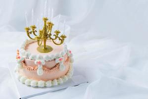 light pink vintage butter cream cake with candle on white cloth background, luxury cake photo