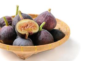 Fresh purple fig fruit and slices in bamboo basket isolated on white background, photo