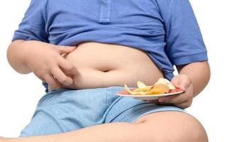 Obese fat boy holding potato chips isolated, junk food concept photo