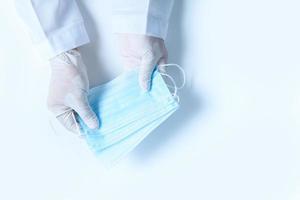 Doctor hands in medical gloves holding surgical  protective mask isolated photo