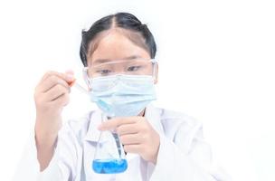 A little scientist is using a droper to drop blue liquid chemical in Erlenmeyer flask isolated photo