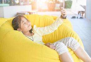 Cute girl relaxing and lies on an air sofa and takes a selfie, photo