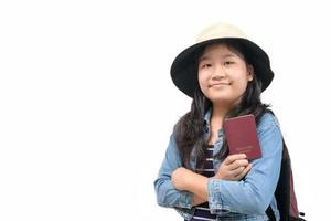 linda asiático niño Listo a viaje vistiendo un sombrero y participación su pasaporte aislado en blanco fondo, foto