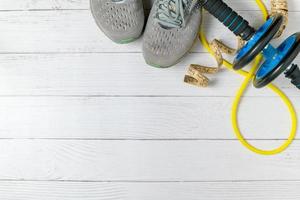 running shoe and abdominal exercises and waist tape on a white wood background photo