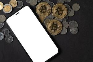 blanco pantalla teléfono inteligente y bitcoin en negro Roca mesa, foto