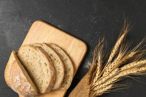 Closed up of sourdough bread on wood plate  and dry barley on black table, photo