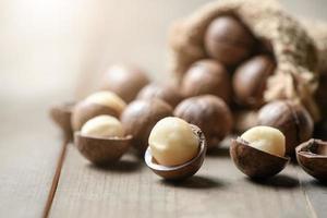 pelado macadamia nueces en madera fondo, macadamia nueces son cargado con flavonoides y tocotrienoles y Rico en corazón saludable monoinsaturado grasas foto