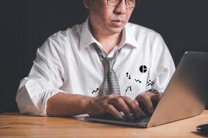 Businessman working on laptop on black background, photo