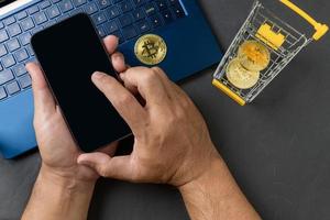 masculino manos utilizando teléfono inteligente para vender o comprar virtual dinero, poco moneda en amarillo carretilla foto
