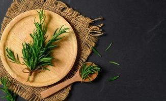 Top view of Branch fresh rosemary in wood plate on black  background. photo