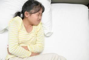 asian girl suffering from stomachache and lying on bed. diarrhea or healthy photo