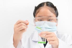 A little scientist is using a dropper to drop green liquid chemical in beaker isolated photo