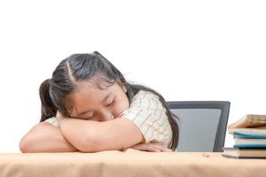 asiático cansado pequeño niña dormido a trabajo escritorio, acostado en mesa aislado en blanco, foto