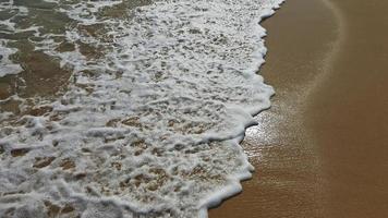 mar agua cubre el arenoso playa. mojado arena. foto
