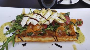 Mozzarella and arugula slices with tomatoes on a waffle. Drenched in balsamic sauce. photo