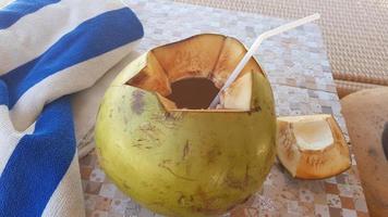 The open coconut is open and lies on the table. Dry towel. photo