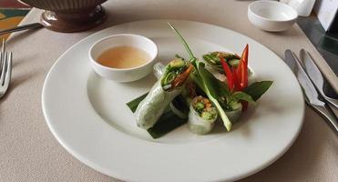 vegetales rollos desde arroz base en blanco lámina. verde cebolla y rojo pimienta, salsa. foto