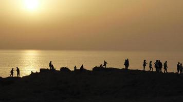 personas reloj el puesta de sol cerca el océano. un oscurecido imagen. foto