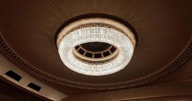 A huge chandelier hangs from the ceiling. Decorated with glass for greater light output. photo