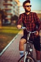 hombre en Gafas de sol montando un bicicleta en ciudad calle foto