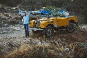 Young stylish man with glasses and bow tie near the old-fashioned SUV photo