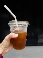 Hand holding glass of iced americano photo