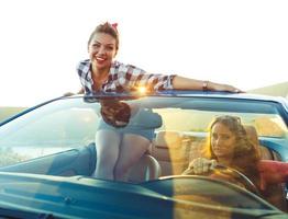 Two young girls driving a cabriolet photo