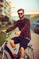 Man in sunglasses riding a bike on city street photo