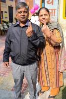 New Delhi, India - December 04 2022 - Unidentified people showing their ink-marked fingers after casting votes in front of polling booth of east Delhi area for MCD local body Elections 2022 photo