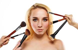 Beautiful young woman with makeup brushes near her face photo