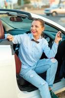 mujer sentado en un convertible coche con el llaves en mano foto