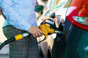 mujer llena gasolina dentro el coche a un gas estación foto