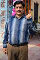 New Delhi, India - December 04 2022 - Unidentified people showing their ink-marked fingers after casting votes in front of polling booth of east Delhi area for MCD local body Elections 2022 photo