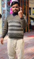 New Delhi, India - December 04 2022 - Unidentified people showing their ink-marked fingers after casting votes in front of polling booth of east Delhi area for MCD local body Elections 2022 photo