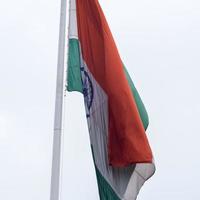 India flag flying high at Connaught Place with pride in blue sky, India flag fluttering, Indian Flag on Independence Day and Republic Day of India, tilt up shot, Waving Indian flag, Har Ghar Tiranga photo