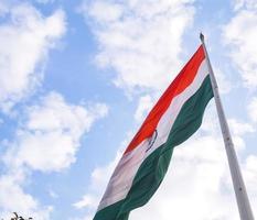 India flag flying high at Connaught Place with pride in blue sky, India flag fluttering, Indian Flag on Independence Day and Republic Day of India, tilt up shot, Waving Indian flag, Har Ghar Tiranga photo