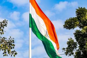 India flag flying high at Connaught Place with pride in blue sky, India flag fluttering, Indian Flag on Independence Day and Republic Day of India, tilt up shot, Waving Indian flag, Har Ghar Tiranga photo