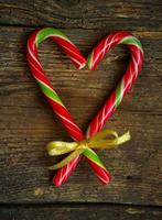 Candy canes in the heart shape on a wooden background photo